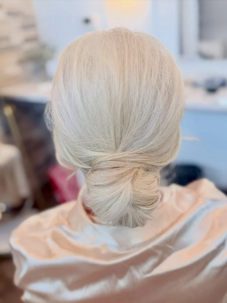 Classic low chignon on platinum blonde hair, smooth twisted knot at the nape