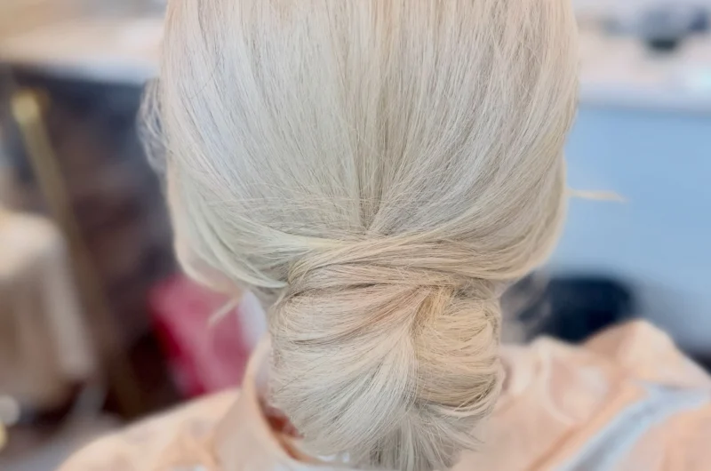 Classic low chignon on platinum blonde hair, smooth twisted knot at the nape