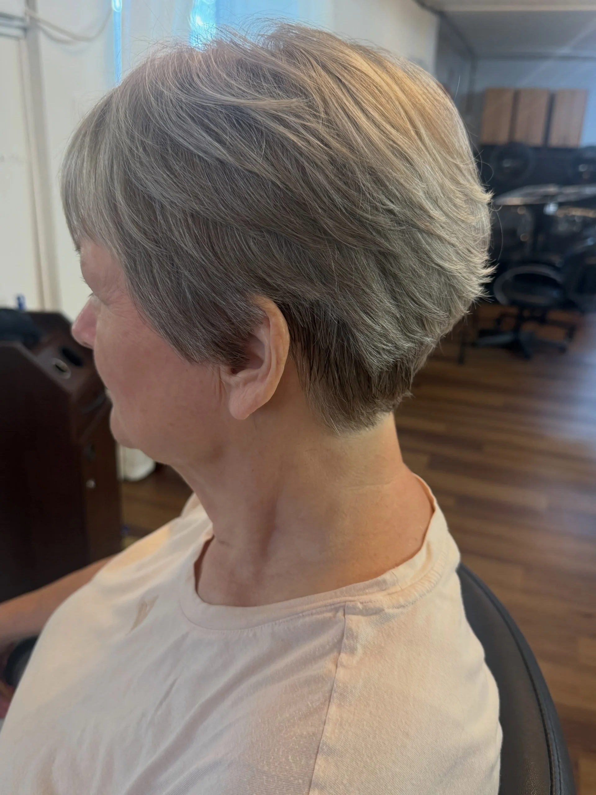 Soft tapered silver pixie cut on an older woman in a salon