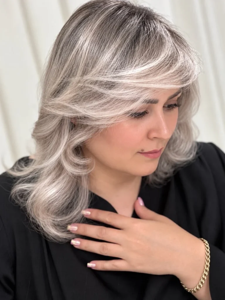 Voluminous layered blowout on silver grey hair with a side part