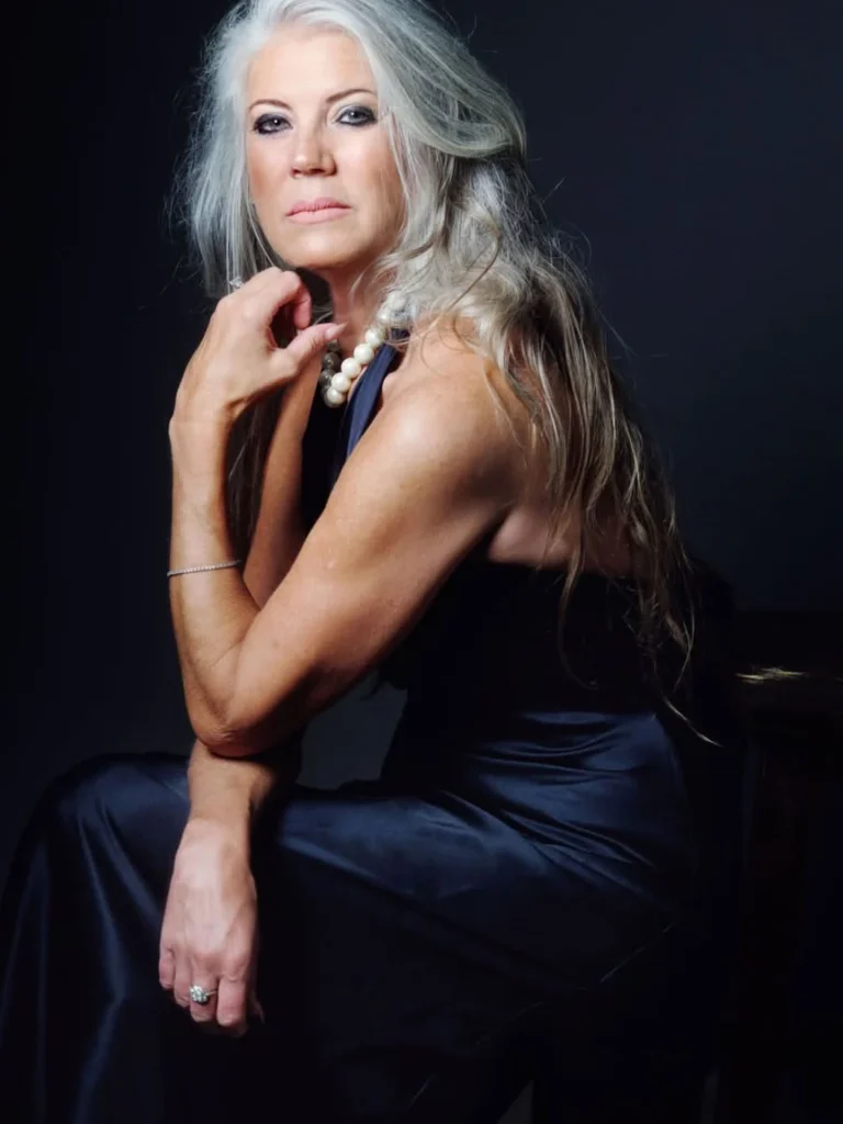 Romantic loose curls on long silver hair, mature woman in a navy gown