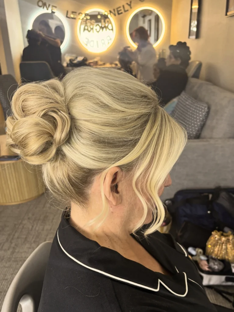 Asymmetric side bun with a loose tendril on blonde hair