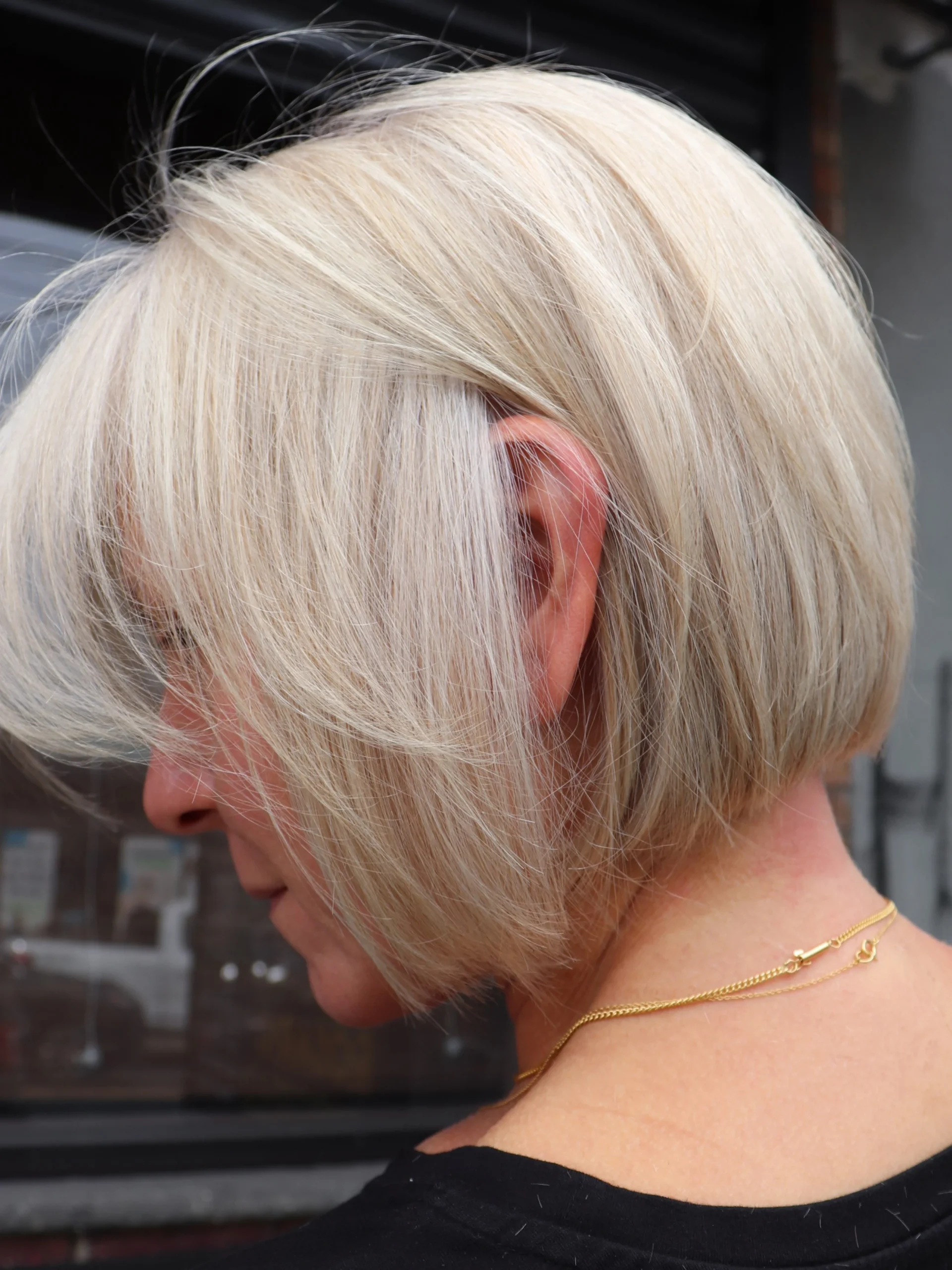 Grey blending platinum French bob on an older woman, side view