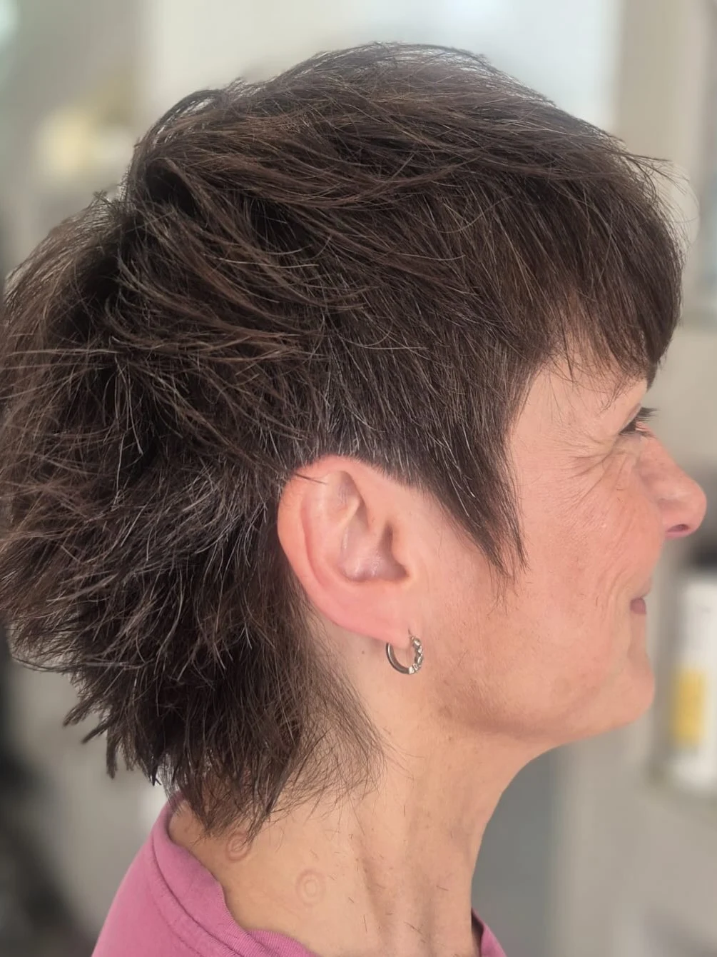 Choppy pixie cut with textured dark layers on an older woman