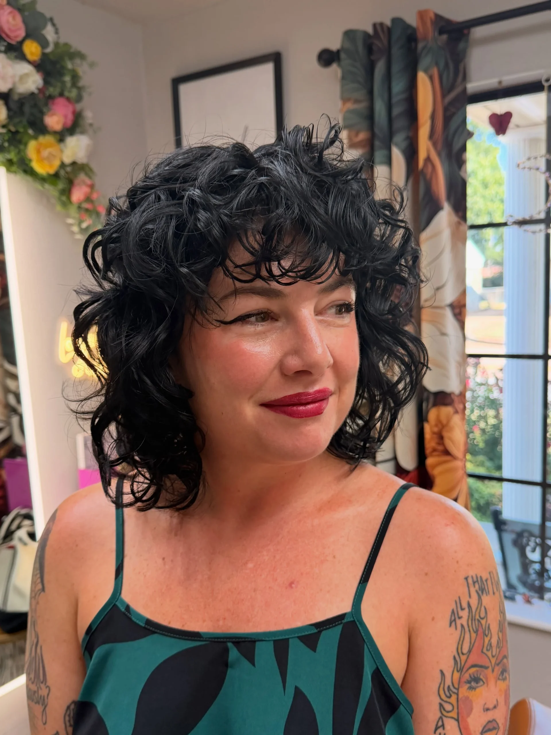 Curly bob with bangs in a salon, worn by a smiling woman